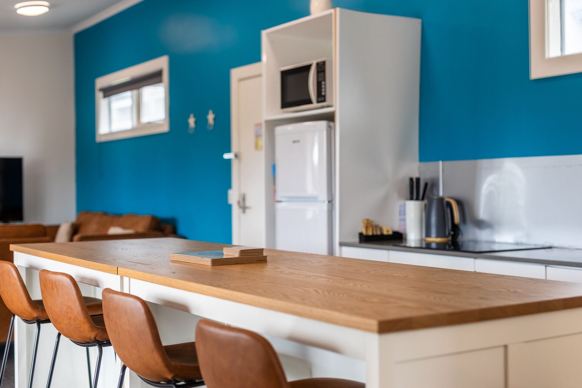 A modern kitchen with a wooden countertop, white cabinets, and a blue accent wall.