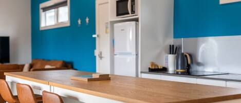 A modern kitchen with a wooden countertop, white cabinets, and a blue accent wall.