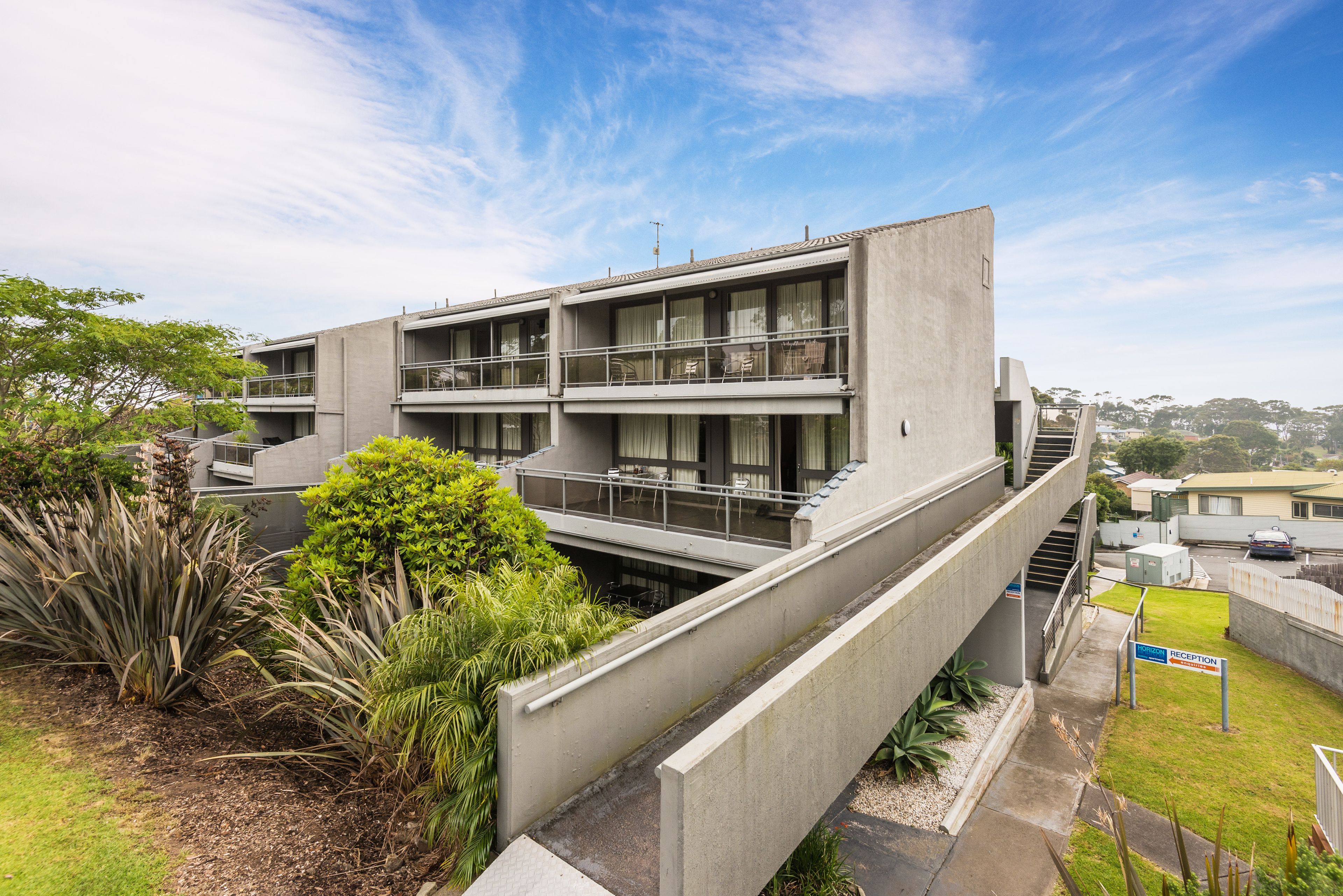 A modern building with a concrete facade, multiple balconies, and a reception area.