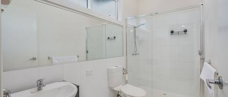 A modern bathroom with a glass-enclosed shower, a sink with a marble countertop, and a toilet.