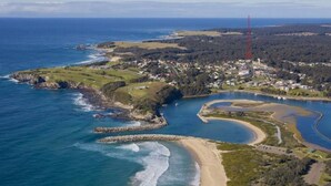An aerial view of a coastal town with a beach, a river, and a residential area.