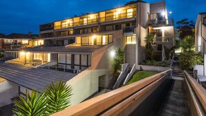 A multi-story hotel with balconies, a rooftop terrace, and a central staircase.
