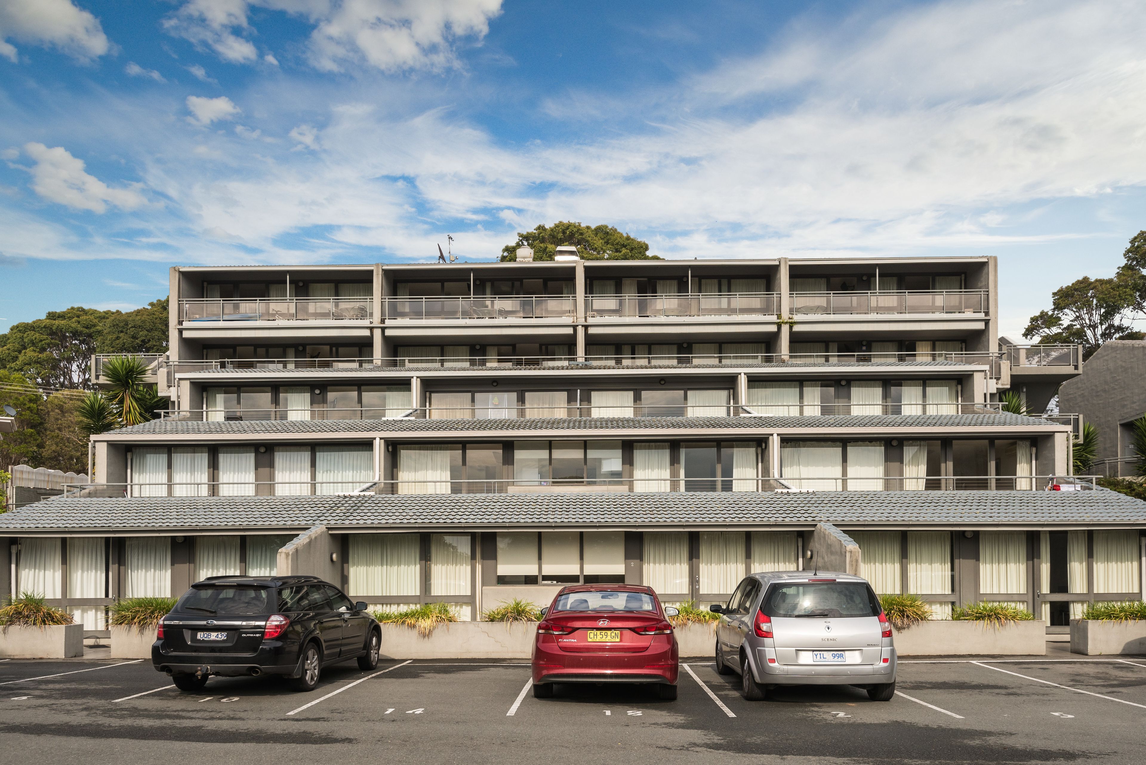 Un immeuble à plusieurs étages avec un parking situé devant.