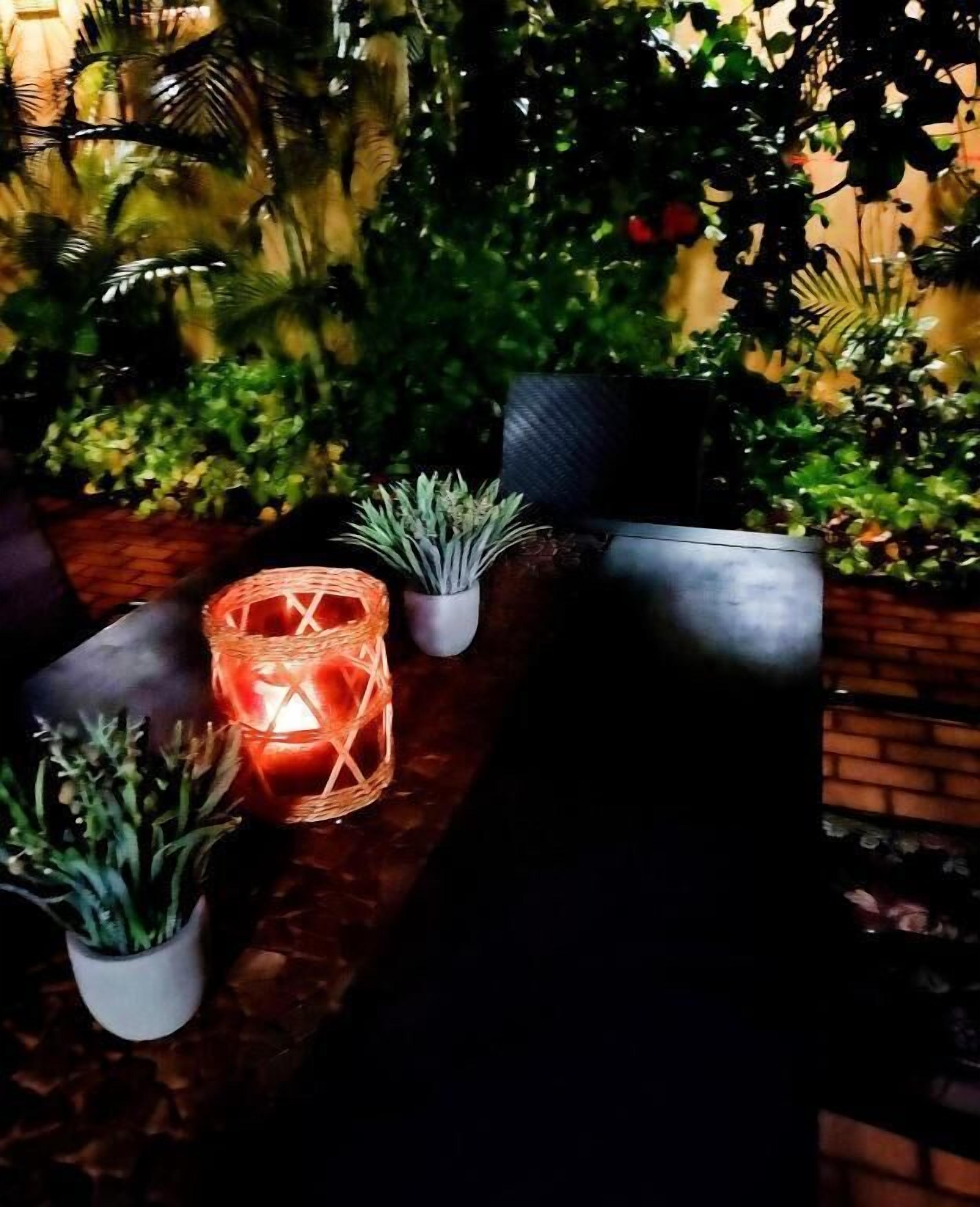 A table with potted plants and a candle in a basket.