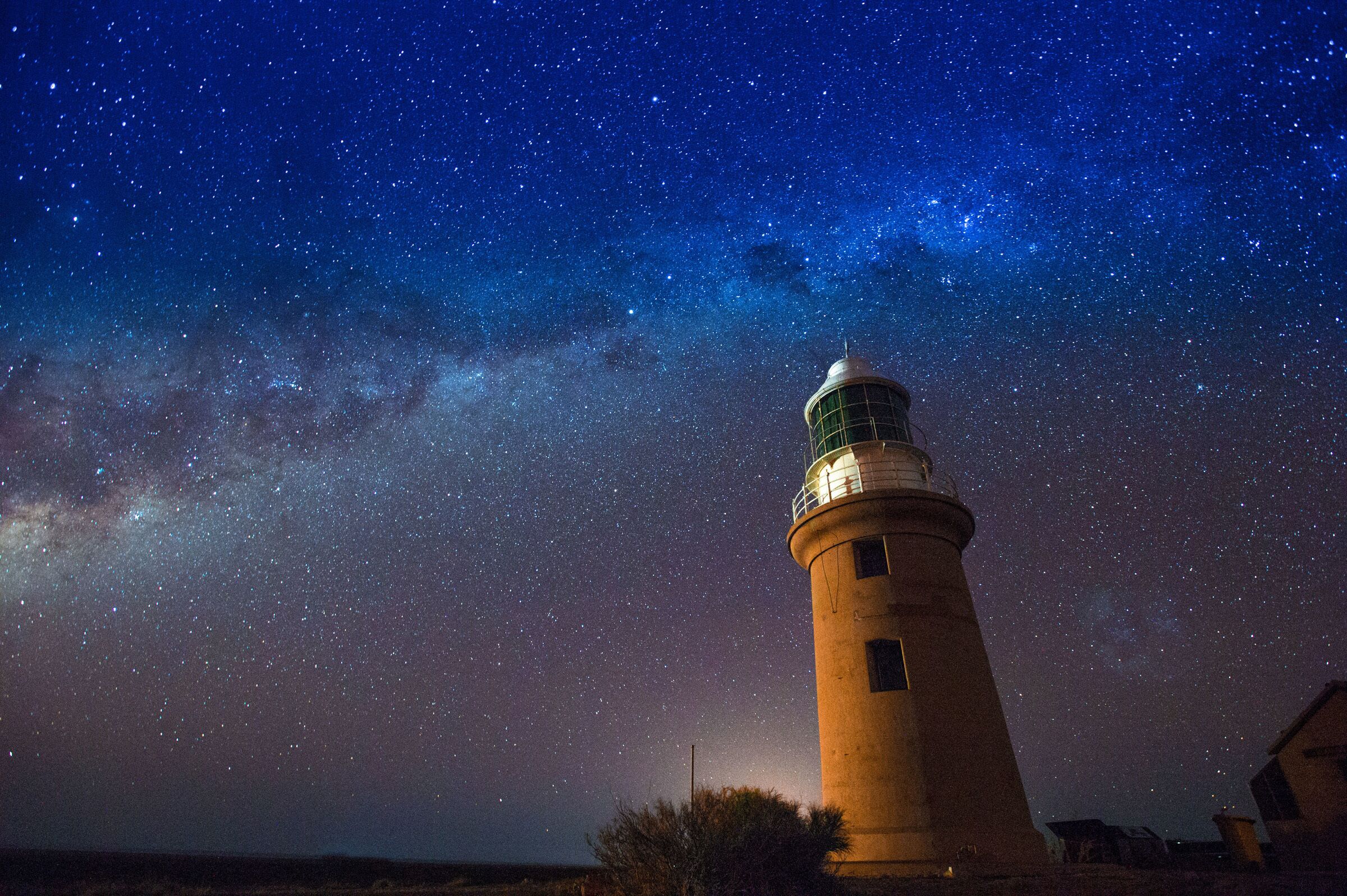 A lighthouse under a starry night sky.