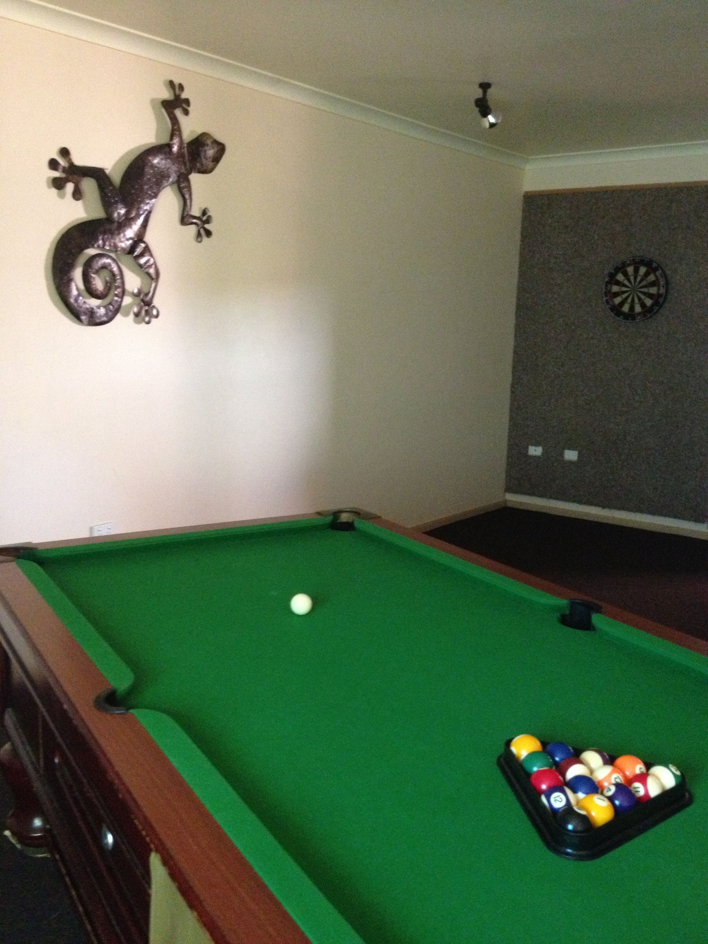 Ein Billardtisch mit grüner Spieloberfläche, einem weißen Queeball und einer Pyramide aus Billardkugeln.
