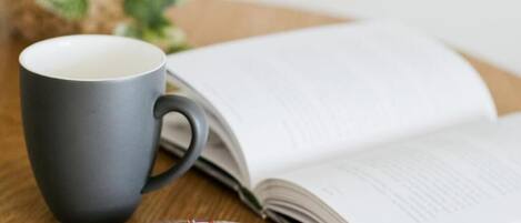 A book, a mug, and a packet of biscuits on a wooden table.