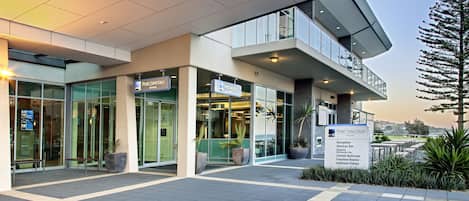 The exterior of the Port Lincoln Hotel with a modern design, including a reception area, glass doors, and a balcony.
