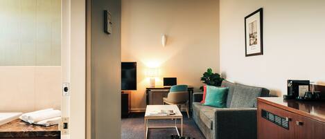 A modern living room with a sofa, a coffee table, a TV, and a lamp.