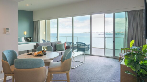 Quarto moderno com varanda, área de refeições e sala de estar com vista para o mar.