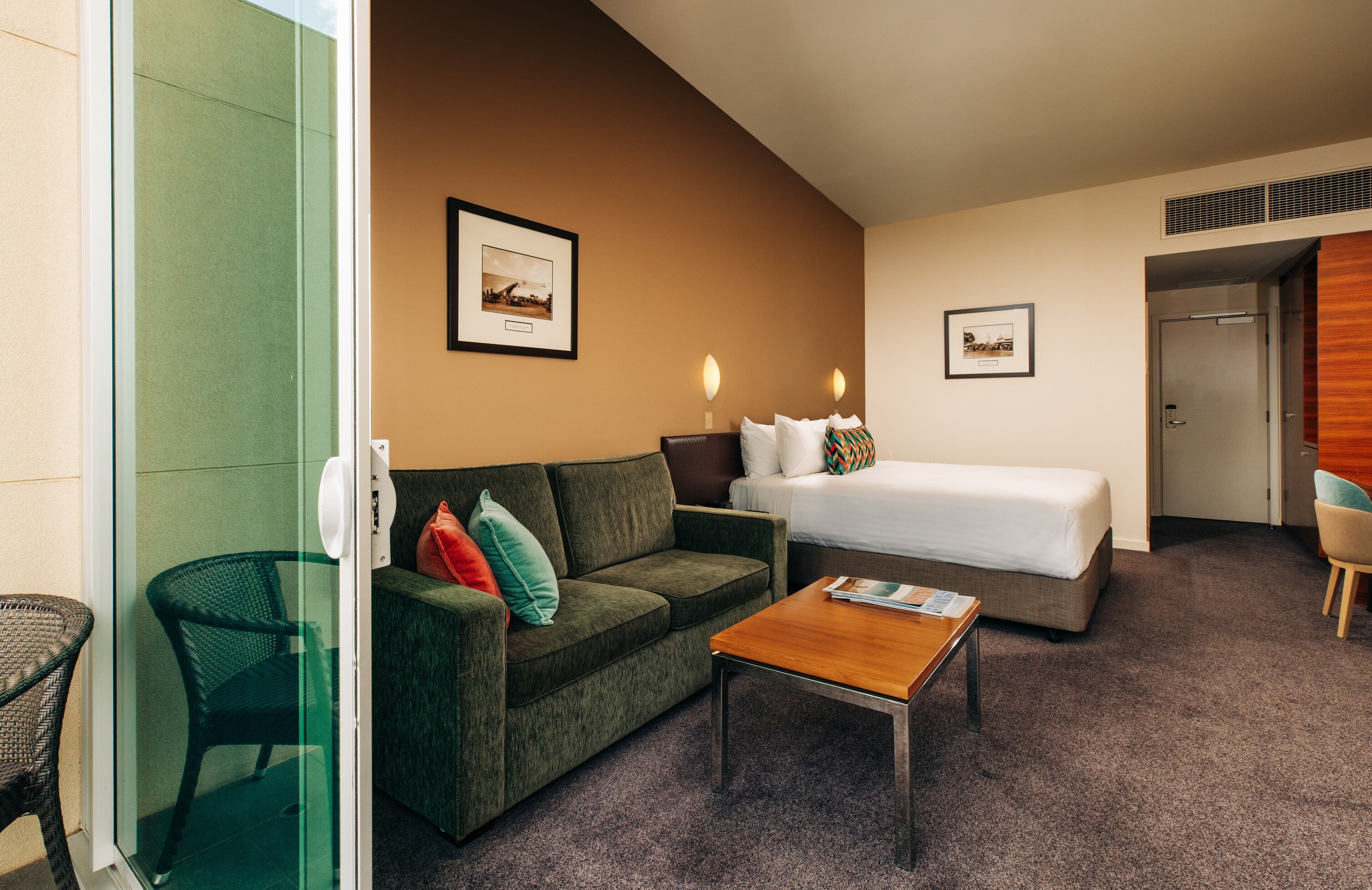 A hotel room with a bed, a sofa, a coffee table, and a chair.