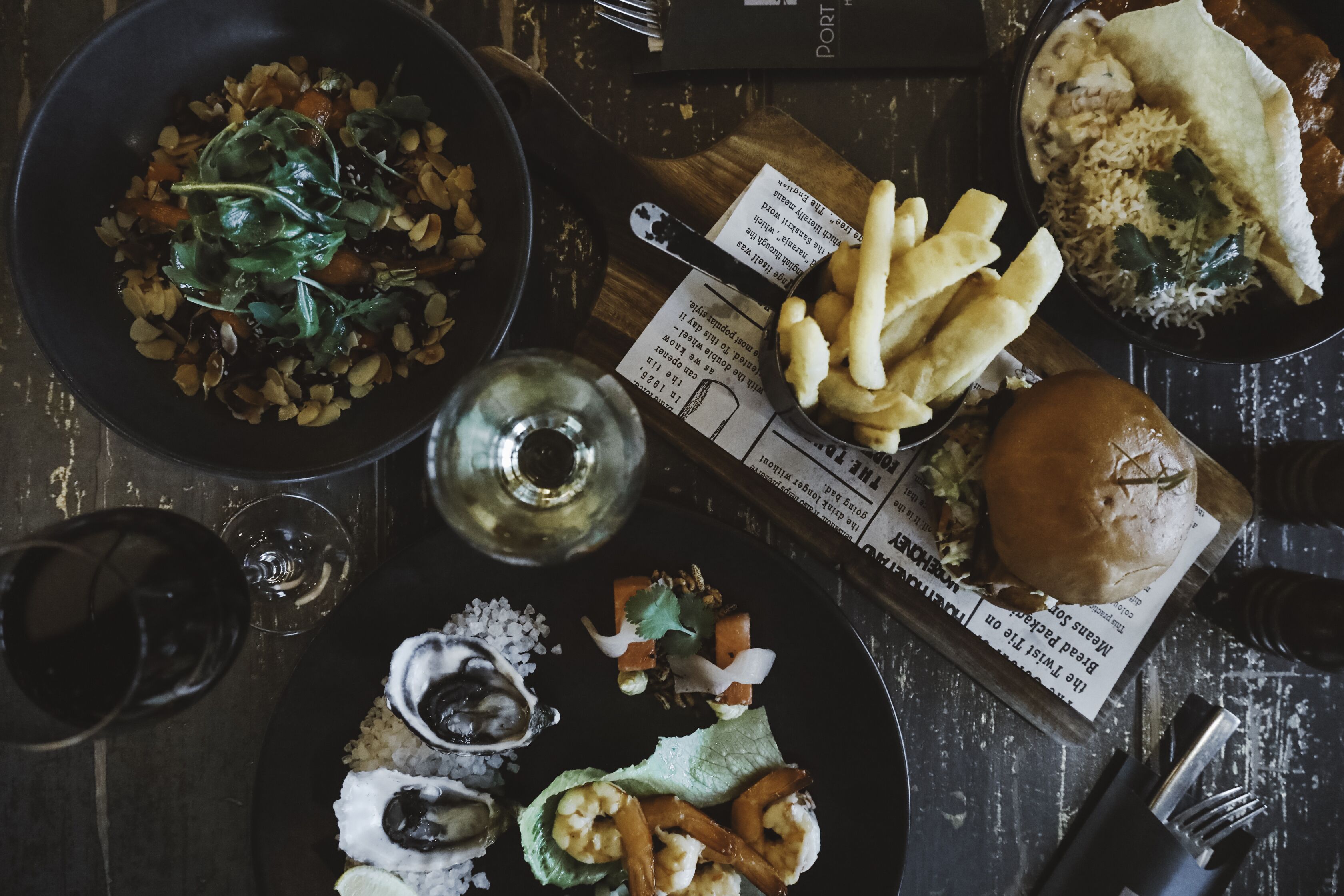A table with various dishes including a burger, fries, and a bowl of salad.