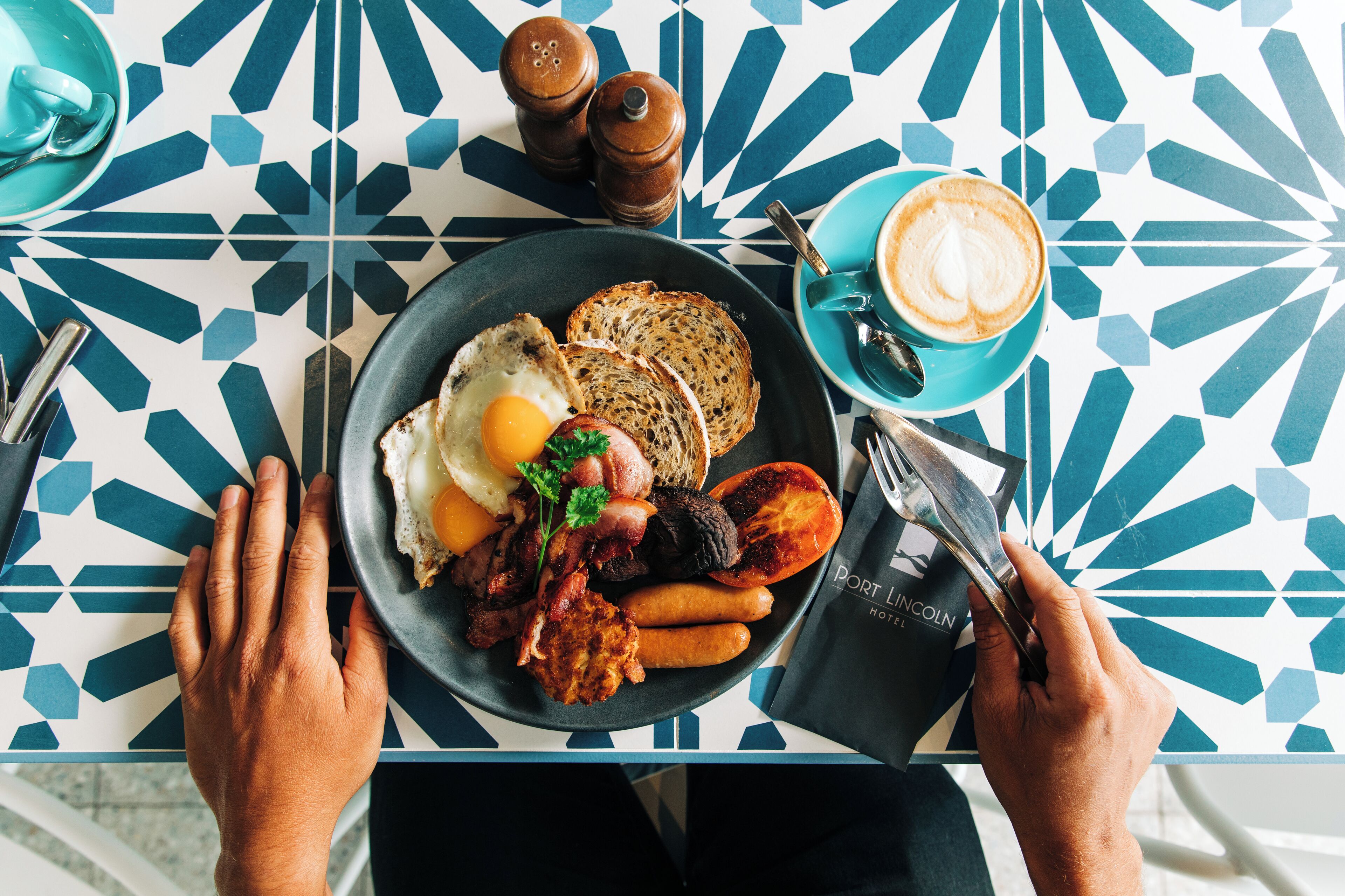 Un plato de desayuno con huevos, salchichas y tostadas sobre una mesa con un diseño geométrico.