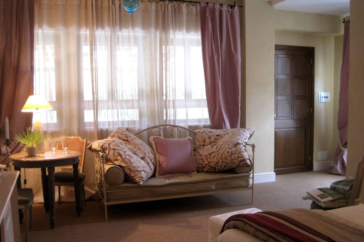 Un salón acogedor con un sofá, una mesita redonda con una lámpara y una silla.