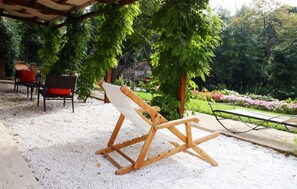 Una silla de madera con un cojín blanco en un jardín con una pérgola.