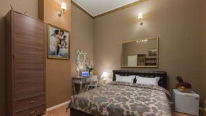 A bedroom with a large bed, a wardrobe, a vanity with a mirror, and a small refrigerator. - Vila Elat (Chisinau)
