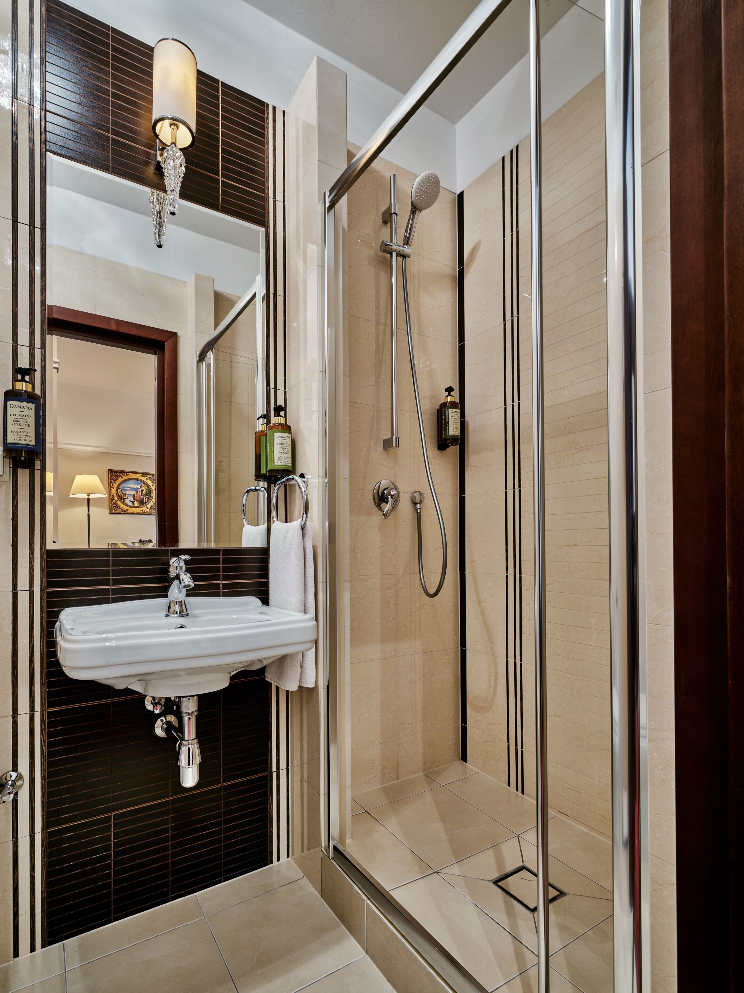 A modern bathroom with a glass-enclosed shower, a white sink, and a mirror above.