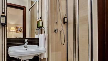 A modern bathroom with a glass-enclosed shower, a white sink, and a mirror above.