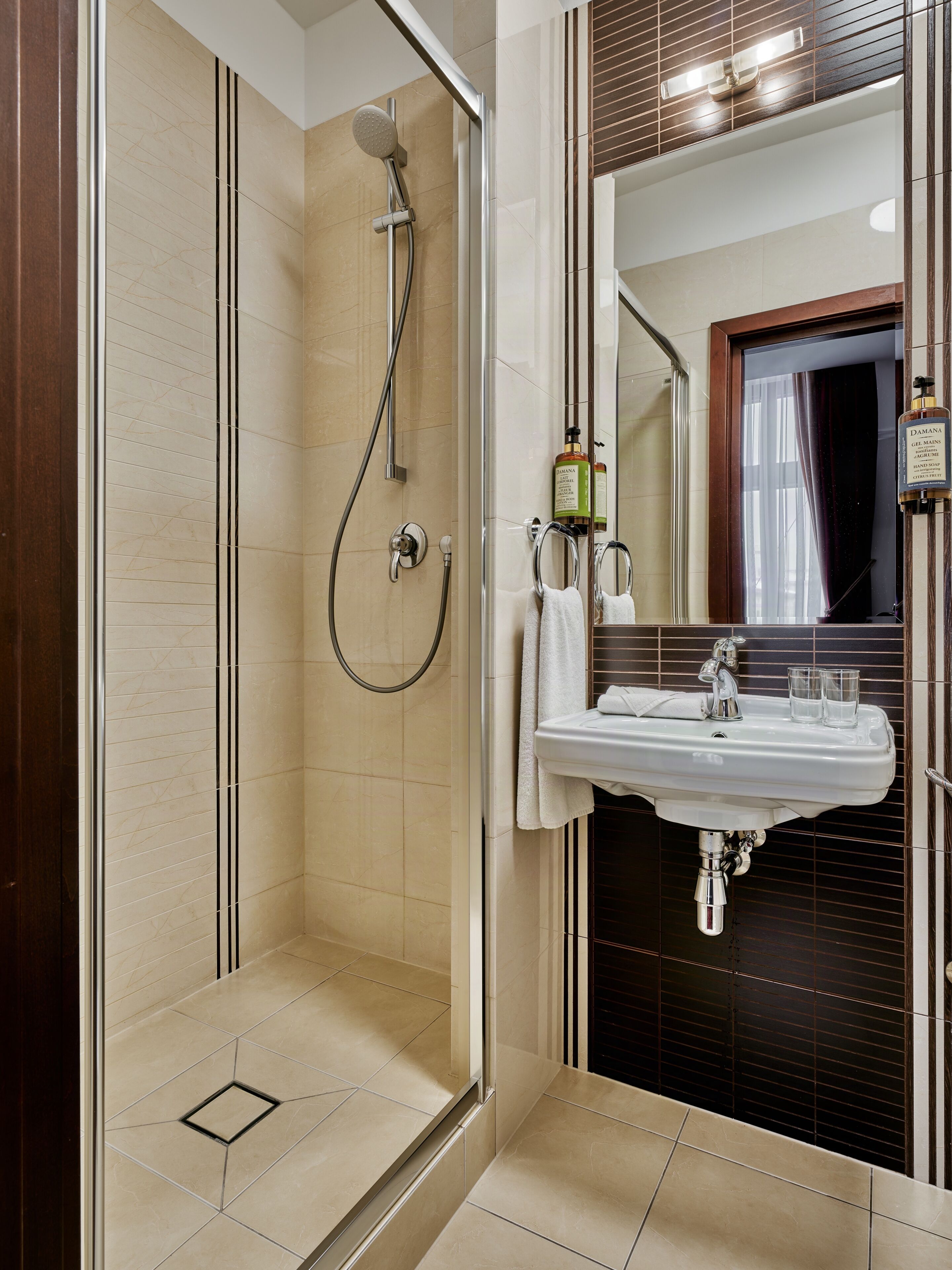 A bathroom with a glass-enclosed shower, a sink with a mirror, and toiletries.