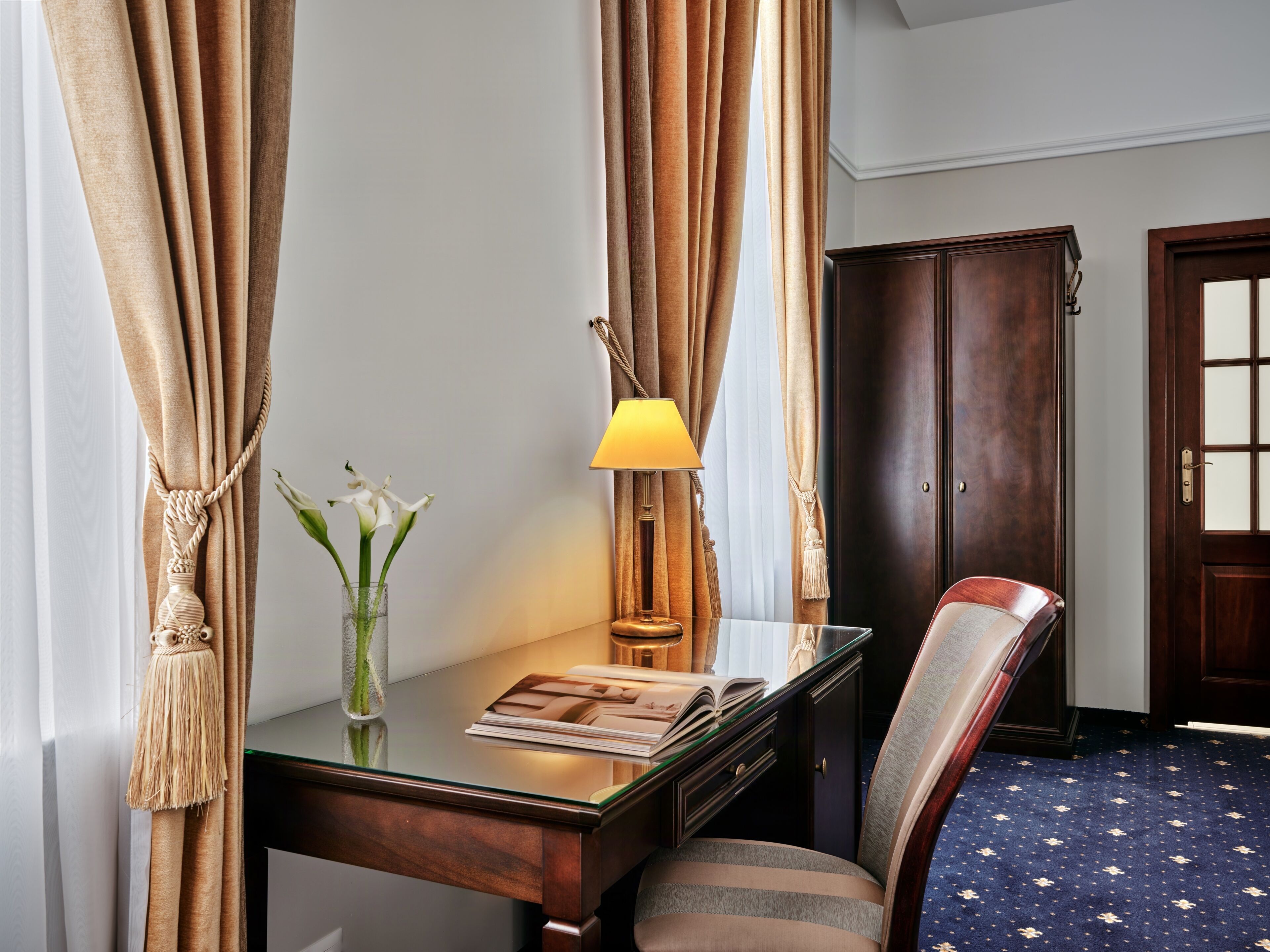 A room with a desk, a chair, a lamp, and a wardrobe.