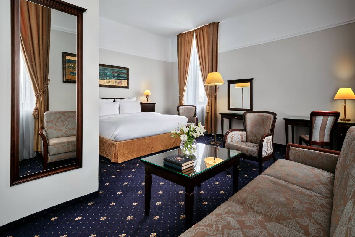 Una habitación de hotel con una cama, dos sillones, un sofá, una mesa de centro y un escritorio.