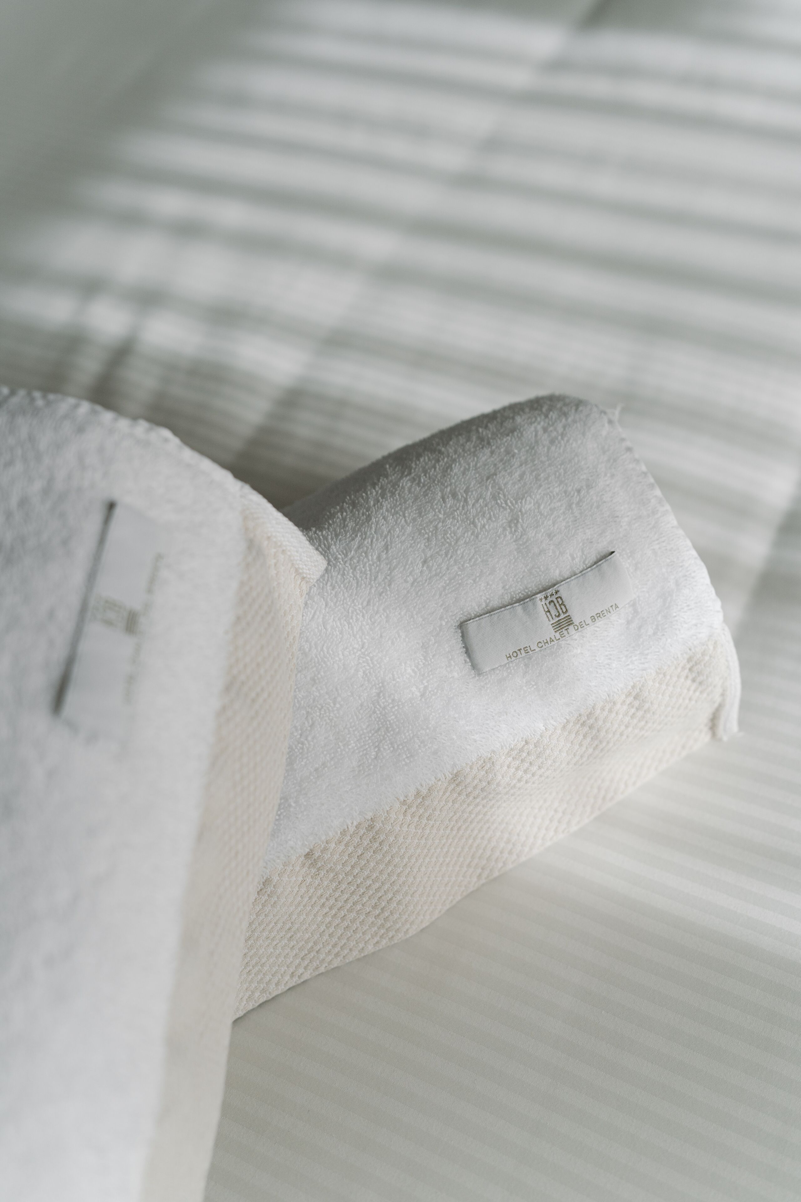 Een witte handdoek met een hotelkaartje op een bed.