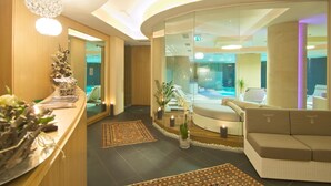 En modern hotellobby med en receptionsdisk, en sittgrupp och en glasvägg som leder ut till en pool.