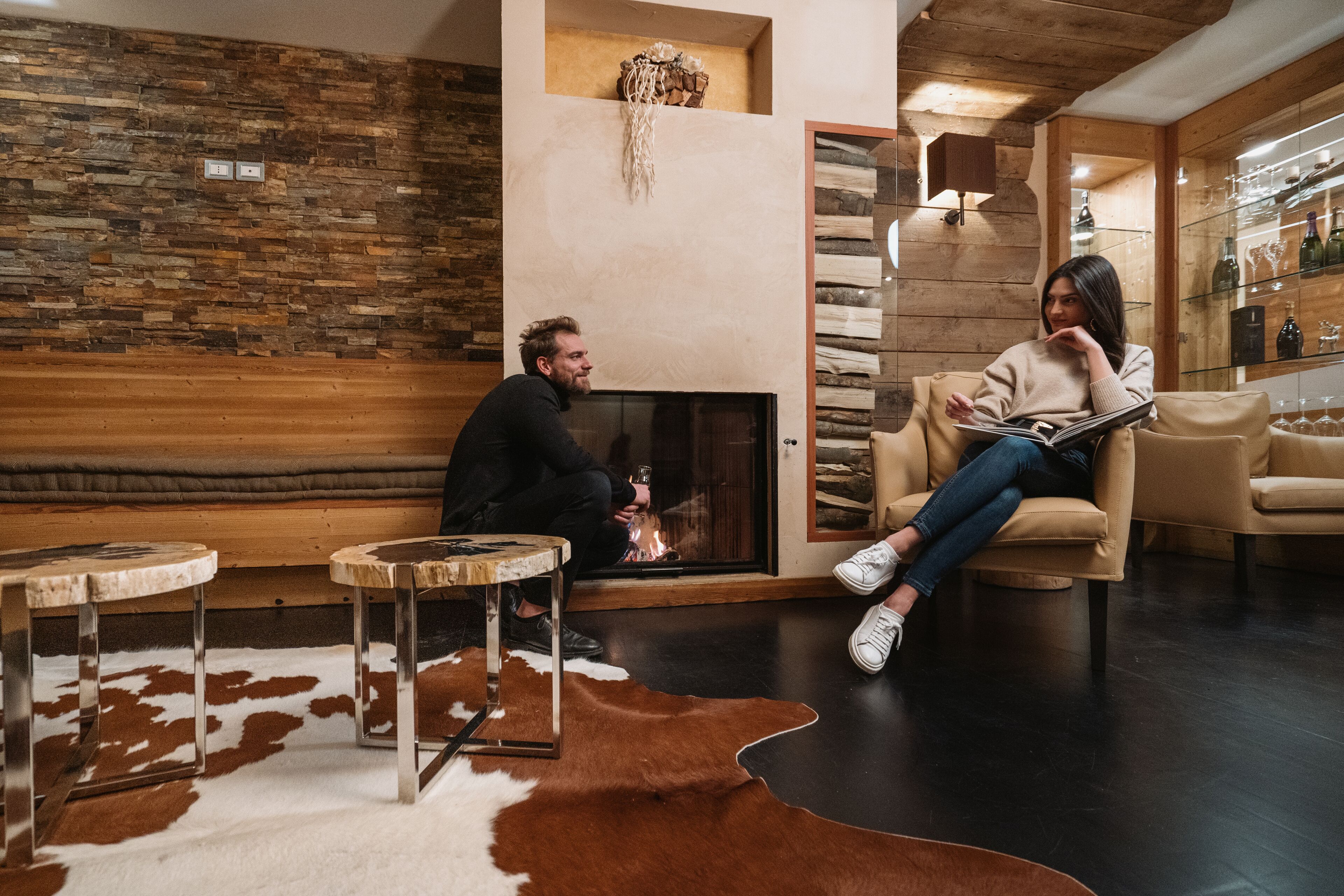 A cozy living room with a fireplace, leather sofas, and a glass display cabinet.
