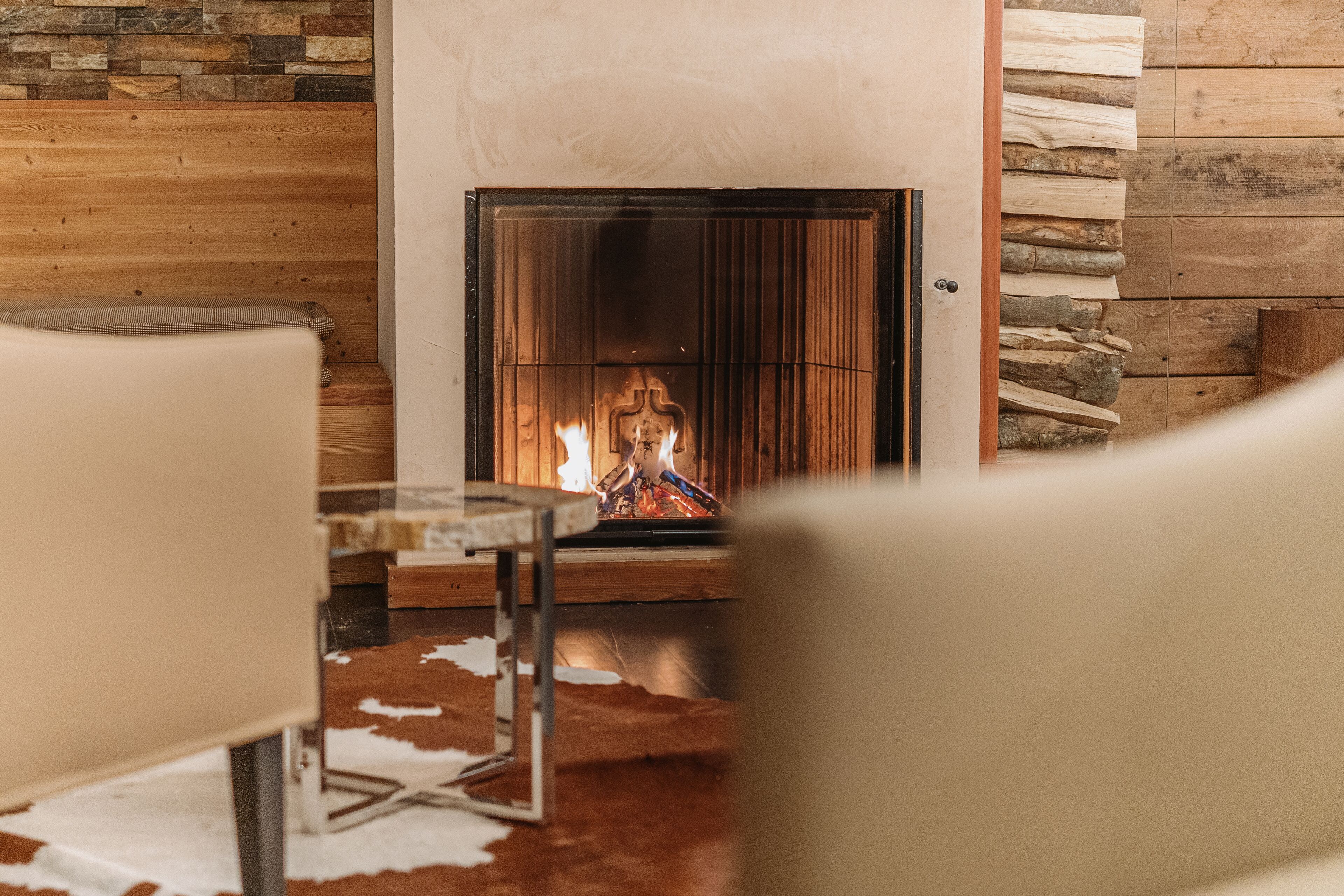 A cozy room with a fireplace, wooden walls, and a cowhide rug.