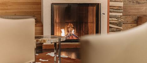 A cozy room with a fireplace, wooden walls, and a cowhide rug.