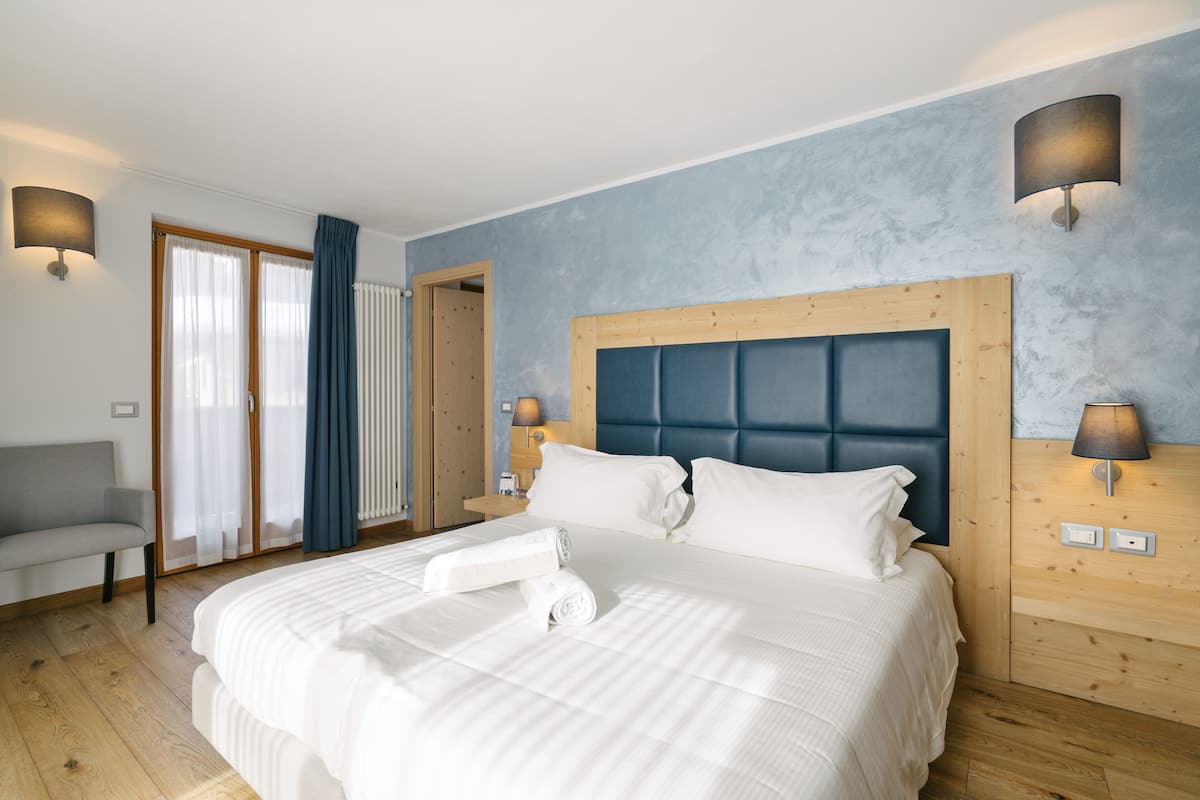 A modern hotel room with a large bed, a wooden headboard, and two bedside lamps.