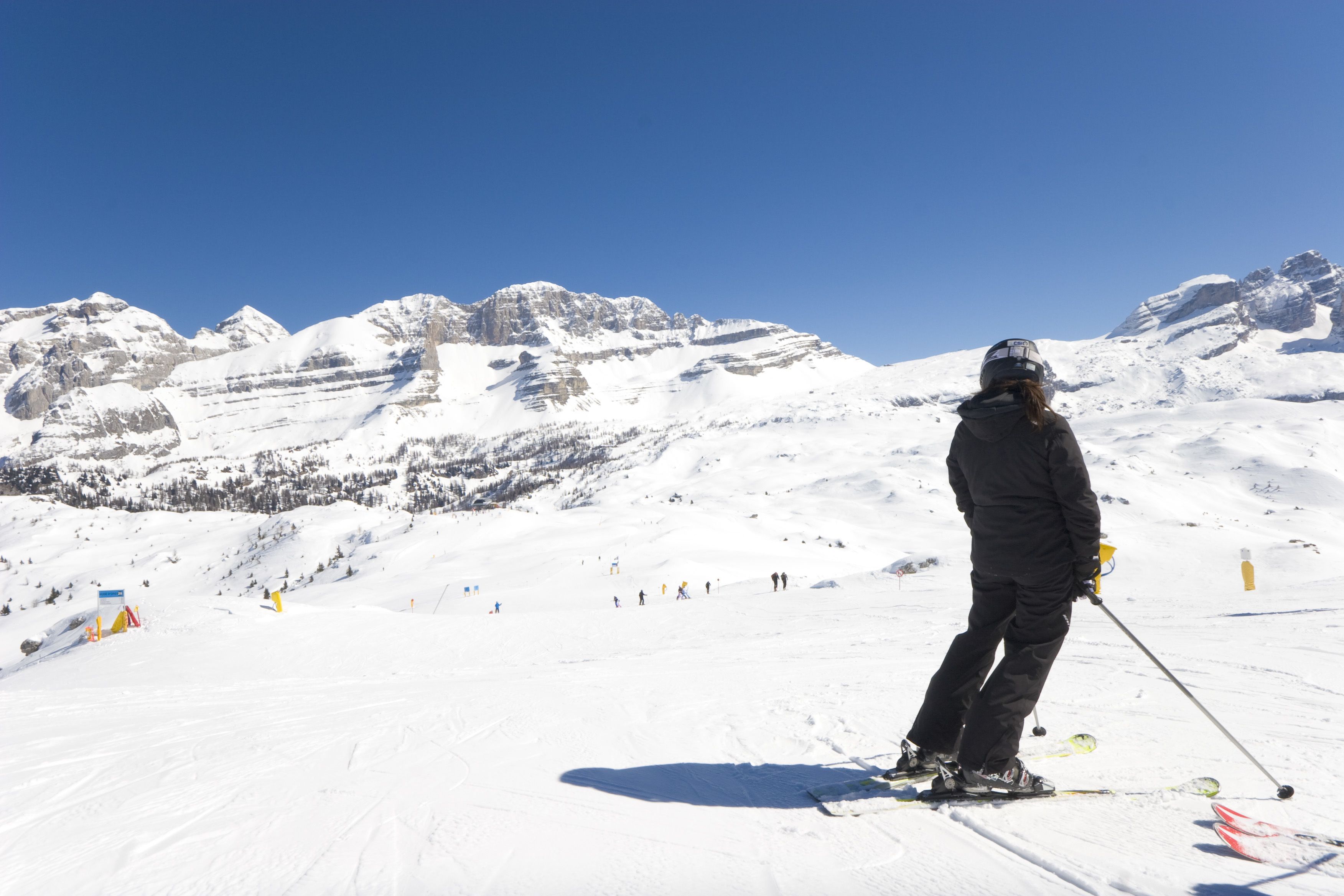 A person skiing on a snow-covered slope with mountains in the background.