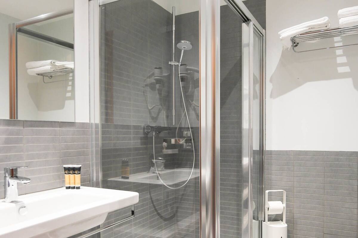 Un baño moderno con cabina de ducha de vidrio, un lavabo blanco y un inodoro.