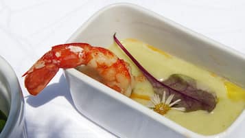 A dish with a shrimp and a flower in a white bowl.