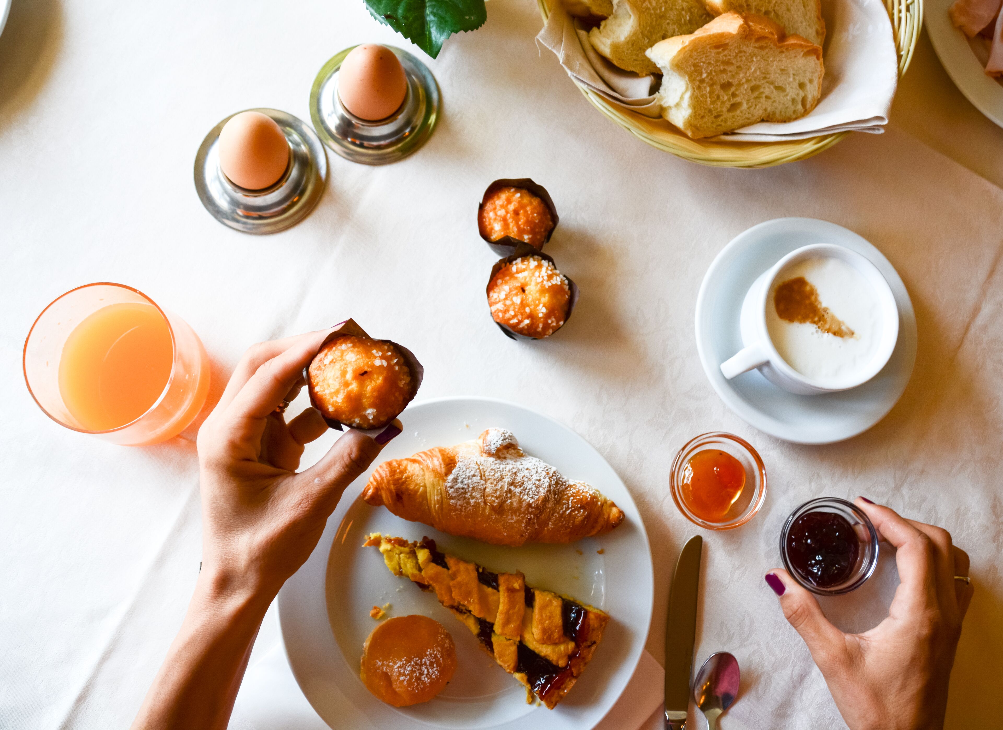Ein Tisch mit Frühstücksangeboten, darunter Gebäck, Brot und eine Tasse Kaffee.