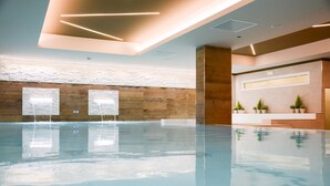 A modern indoor pool area with a wooden wall and a reception desk.