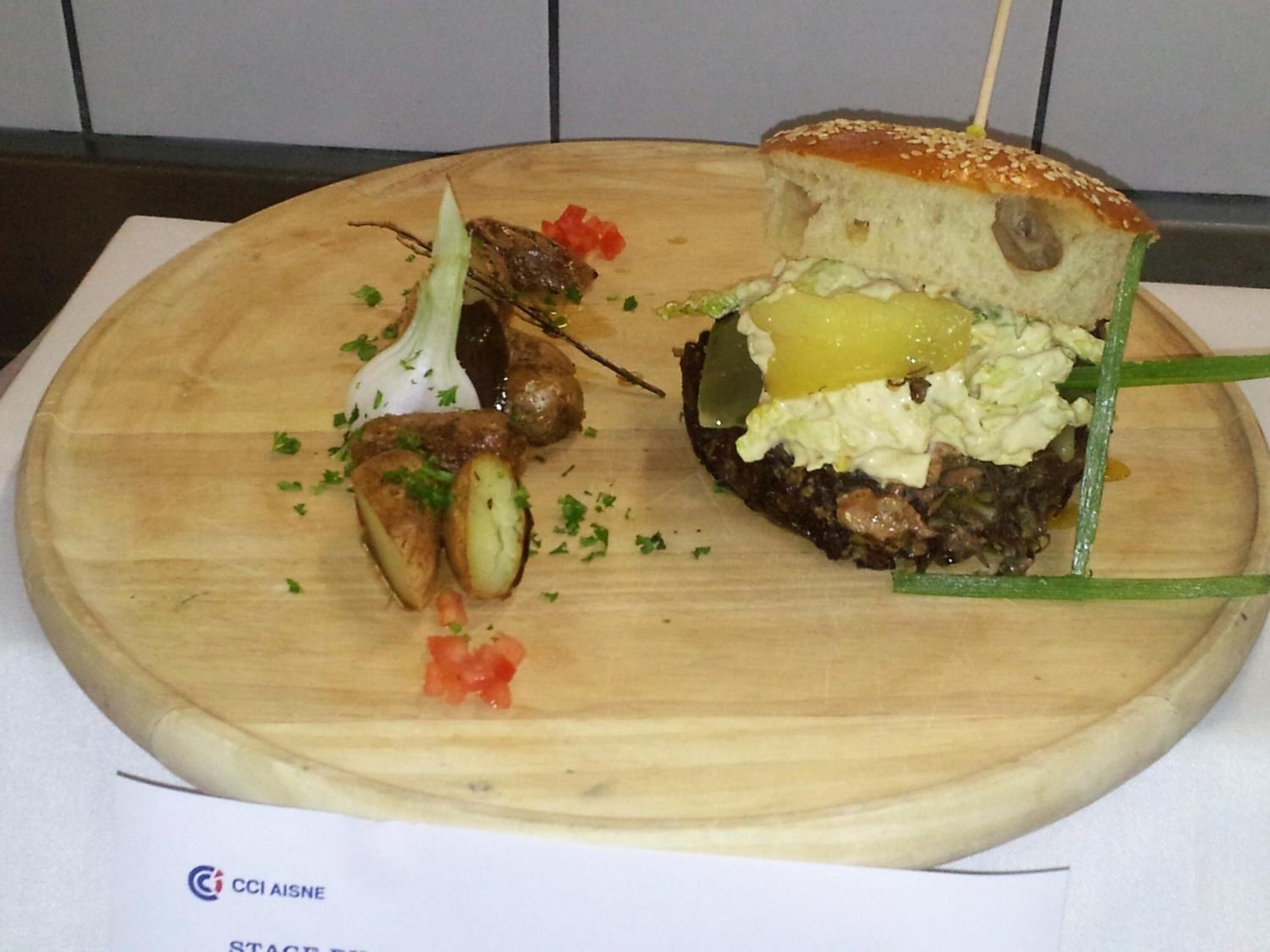 A wooden board with a sandwich and some vegetables.