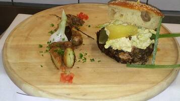 A wooden board with a sandwich and some vegetables.