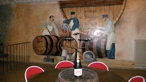Ein Restaurantinneres mit einer Wandmalerei von Barkeepern, Holzbottichen und einer Weinflasche auf dem Tisch.