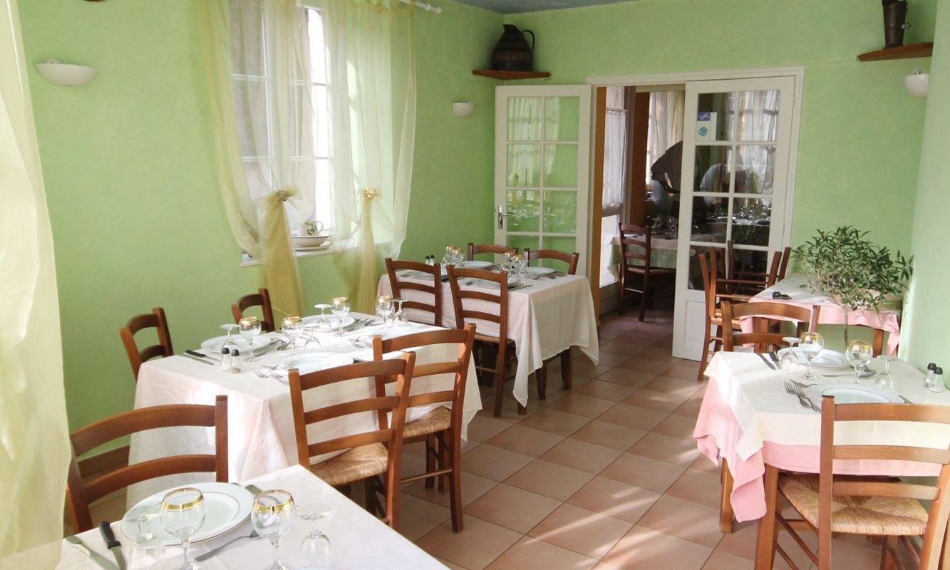 A dining area with multiple tables set for meals, chairs, and a window with curtains.