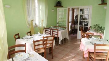 A dining area with multiple tables set for meals, chairs, and a window with curtains.