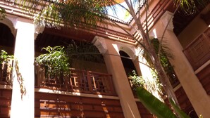 Un patio interior con techo de madera, columnas y plantas en macetas.