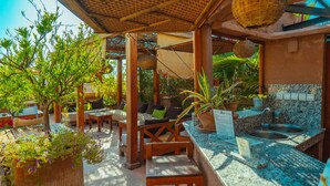 Un espacio de estar al aire libre con muebles de madera y una encimera de piedra con lavamanos.