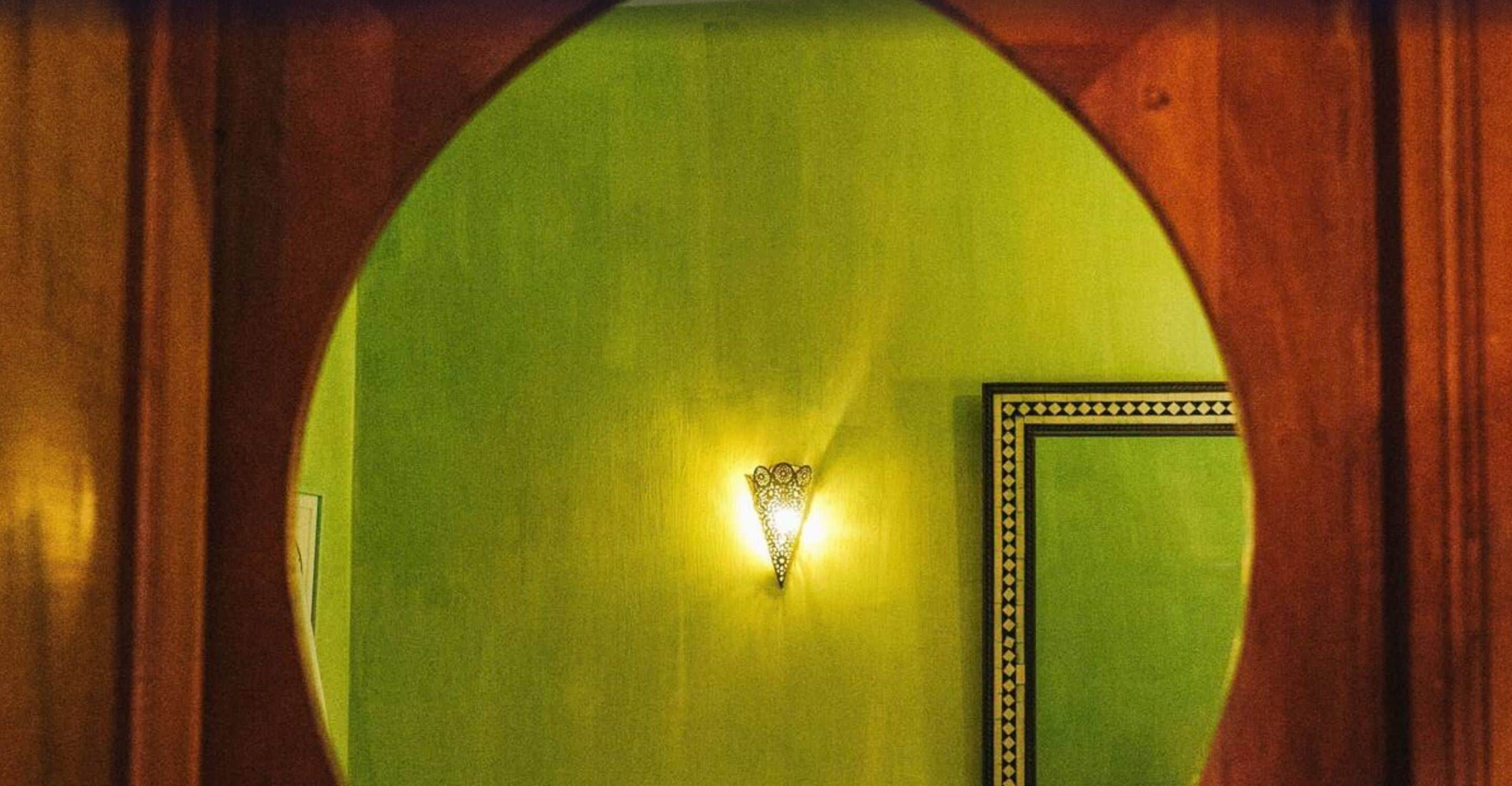 A green wall with a decorative light fixture and a framed picture.