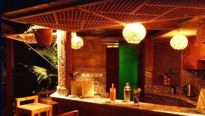 Una zona de bar con mostrador, luces colgantes y un separador verde.