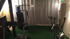 A gym with exercise equipment including a treadmill, elliptical, and weight machine.