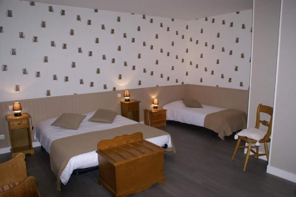 A bedroom with two beds, wooden furniture, and patterned wallpaper.