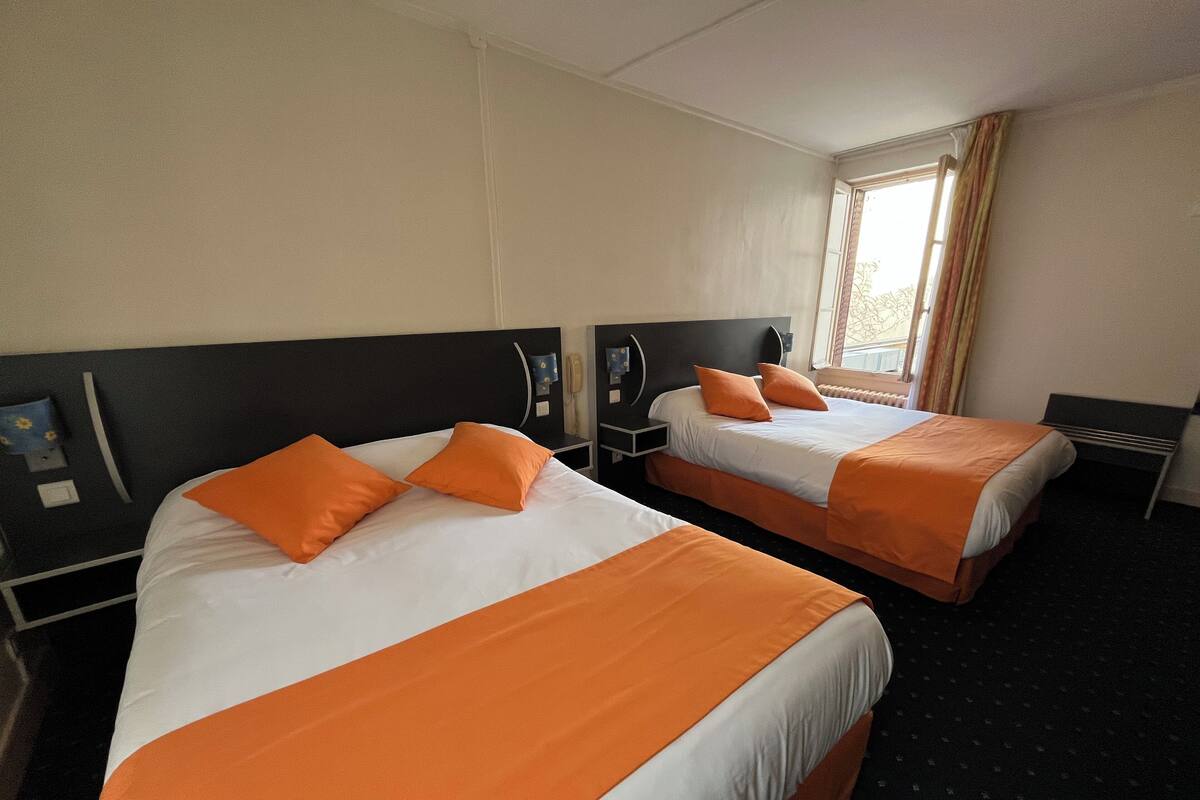 Deux lits doubles avec une literie orange dans une chambre d’hôtel.