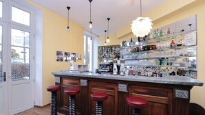A bar area with a wooden counter, four stools, and a variety of bottles and glasses on shelves. - Relais Saint Louis (Belleme)