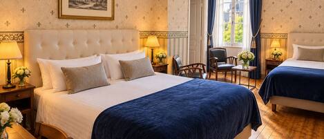 A hotel room with a large bed, two bedside tables, a chair, a window with curtains, and a framed picture on the wall.